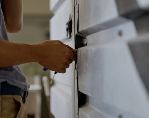 A person using a tool to unlock or repair a metal door or gate.