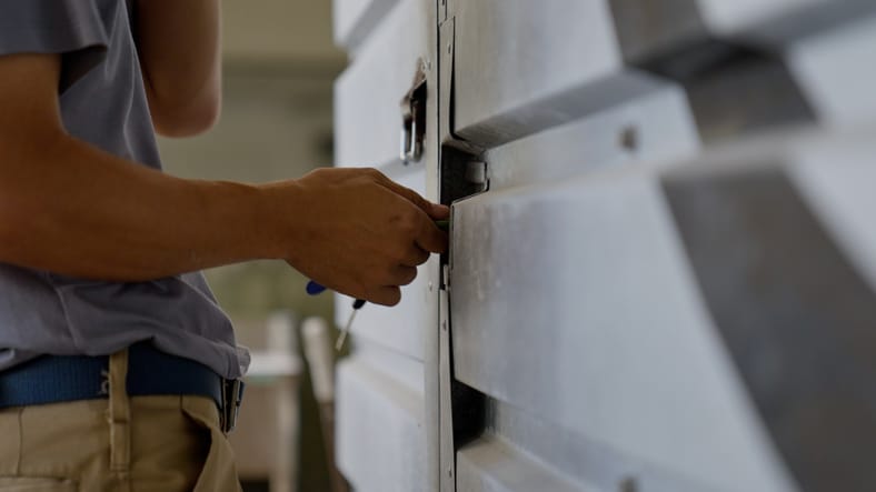 A person using a tool to unlock or repair a metal door or gate.