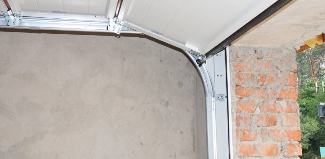 A partially open garage door with exposed brick and plaster walls visible inside and outside the garage.