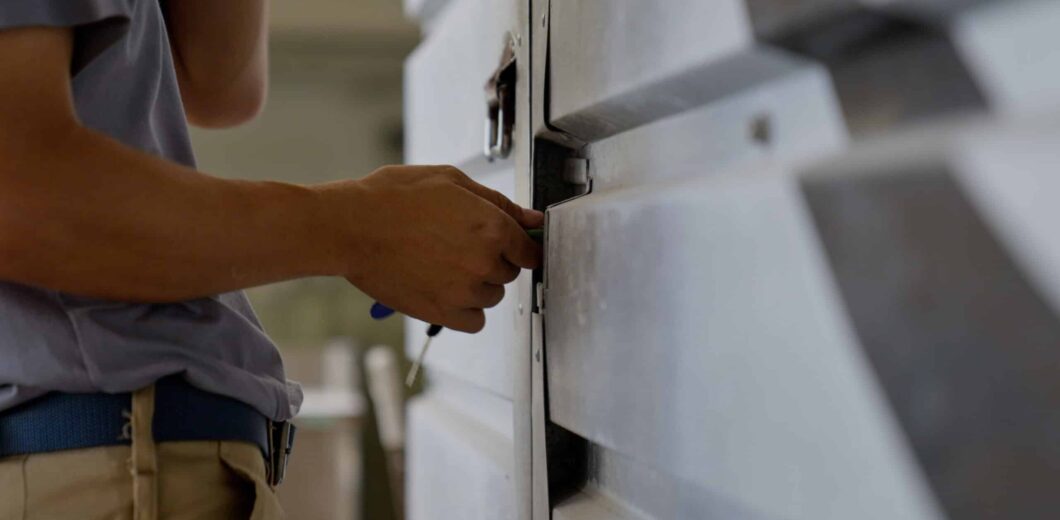 A person uses a tool to unlock or repair a large metal industrial door or panel.