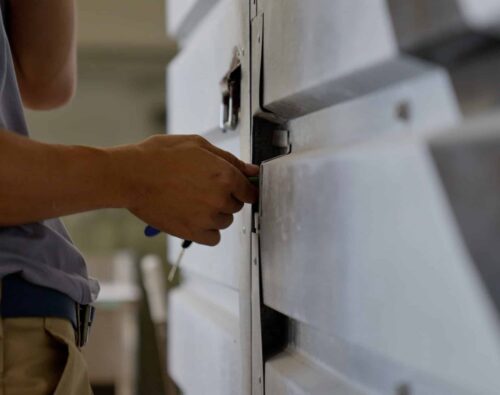 A person uses a tool to unlock or repair a large metal industrial door or panel.