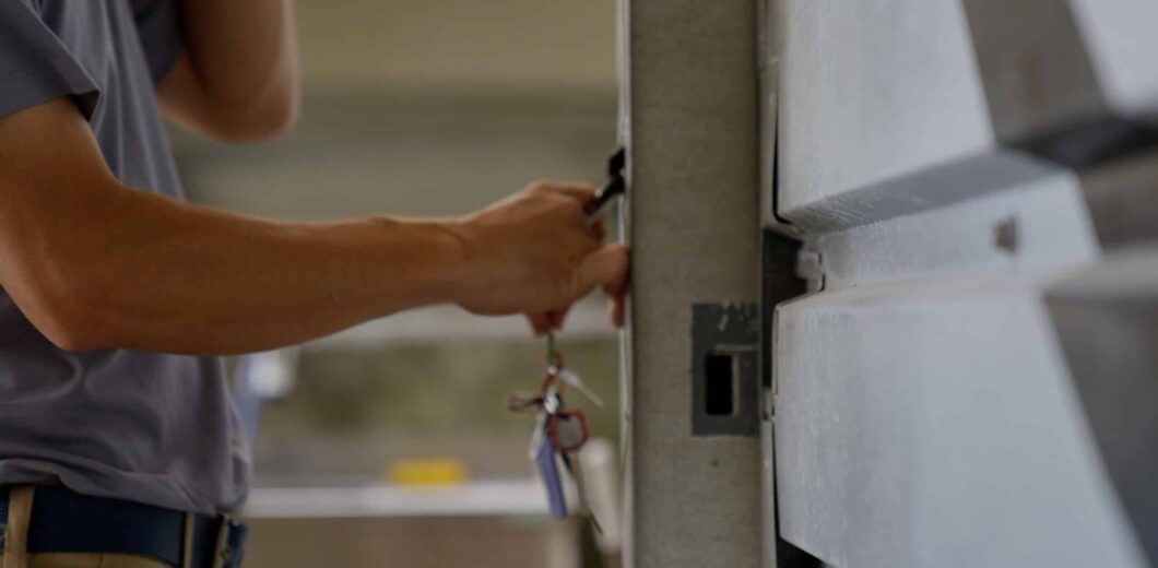 A person holds a set of keys and unlocks a metal door or cabinet with one hand.
