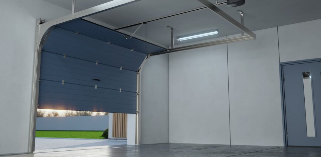 A modern, empty garage with a partially open blue sectional garage door, concrete floor, and white walls.