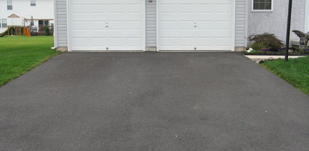a residential asphalt driveway leading to a two-car garage