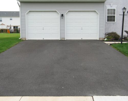 a residential asphalt driveway leading to a two-car garage