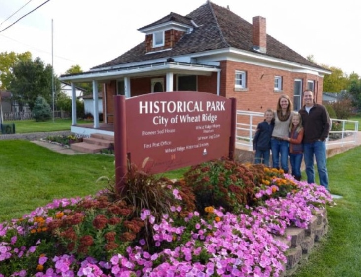 A family of four stands by a red sign reading