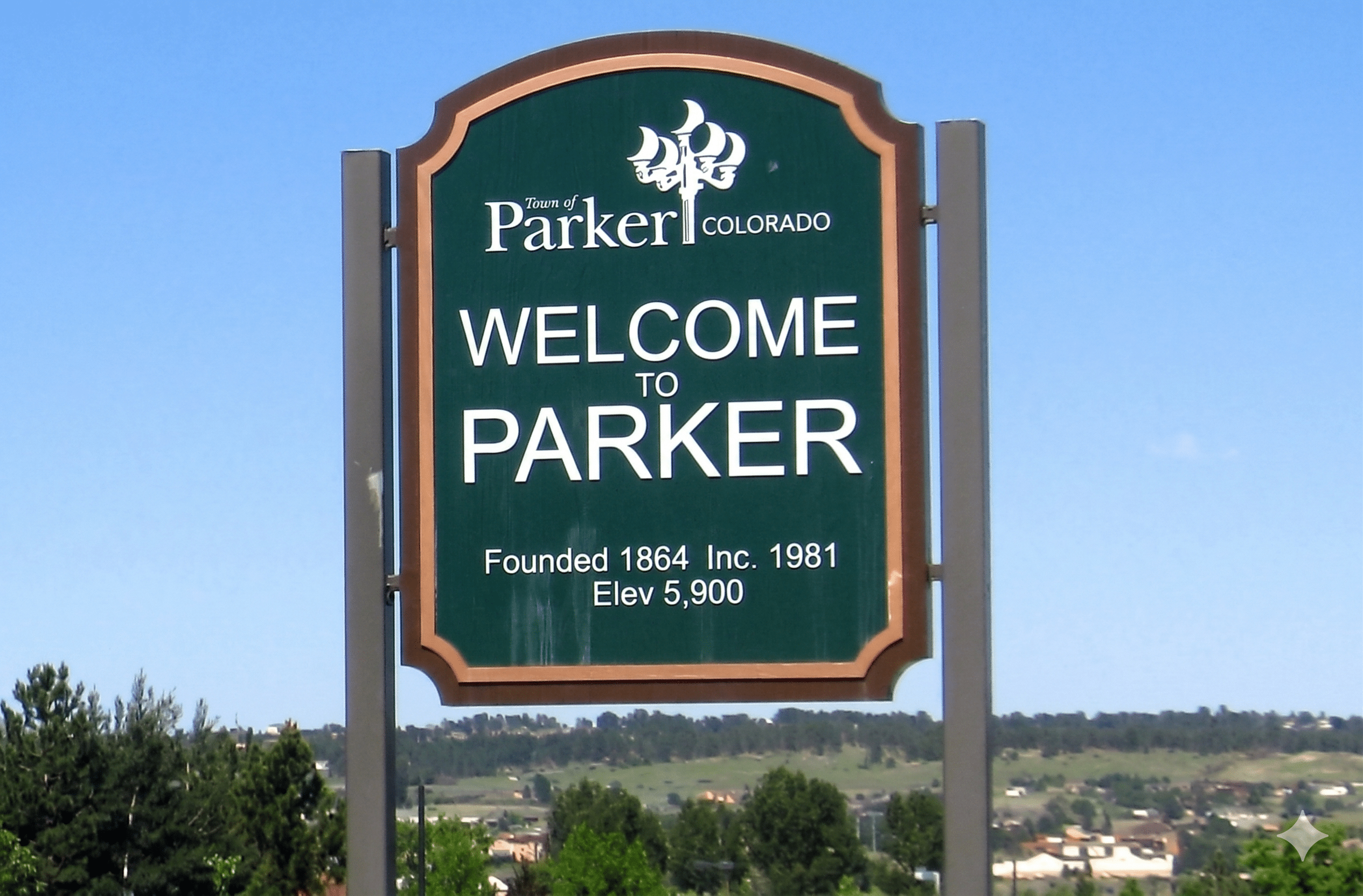 Green Welcome to Parker, Colorado road sign reading Founded 1864, Inc. 1981, Elev 5,900 against a clear blue sky.