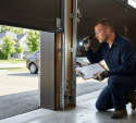 professional garage door technician performing a detailed inspection on a modern residential sectional garage door