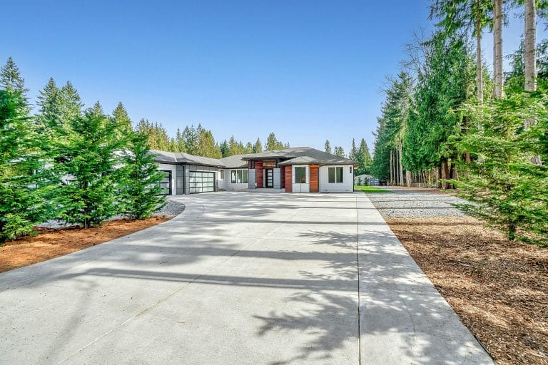 White concrete house near green trees under blue sky