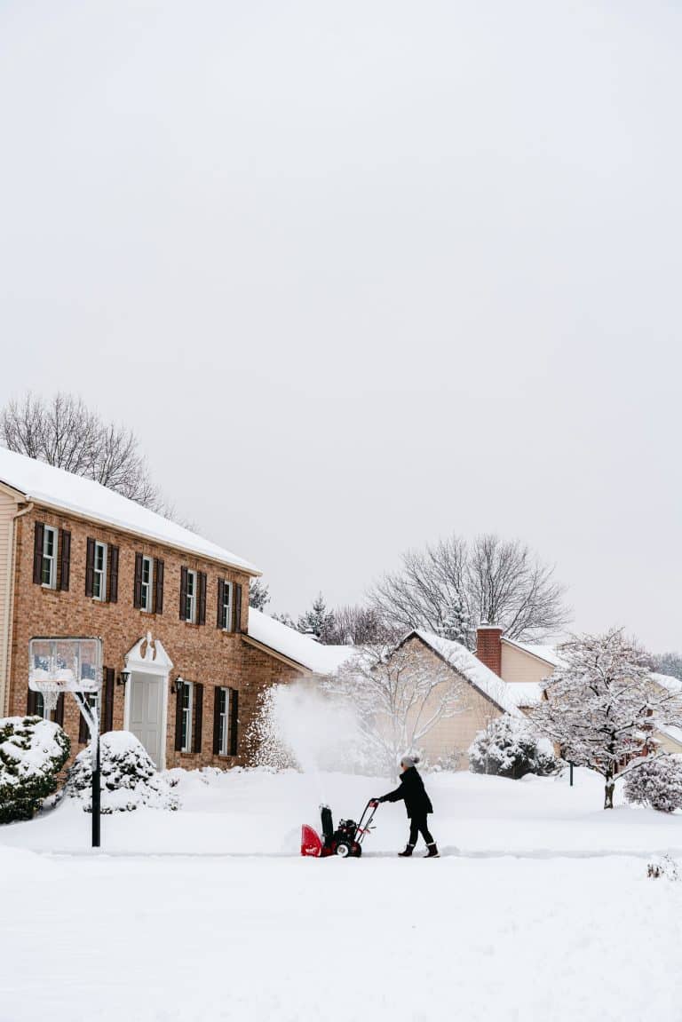 Person clearing snow in front of a brick house