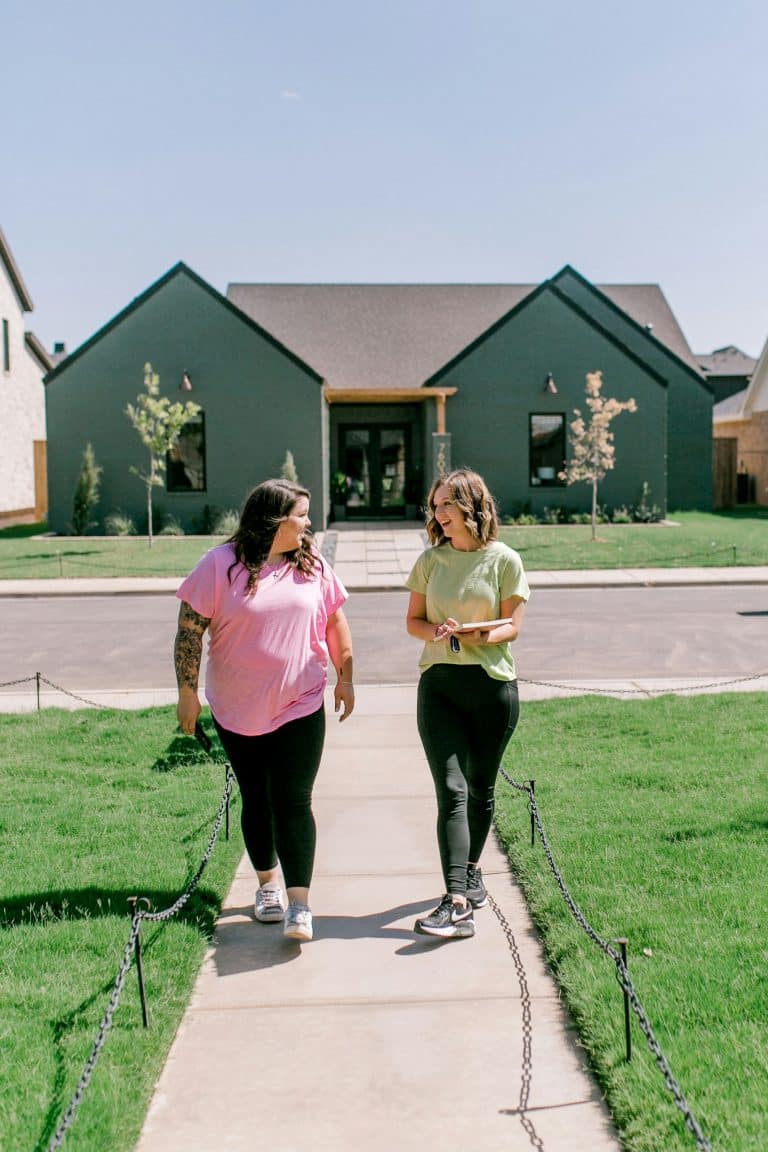 Two people walking past a modern house