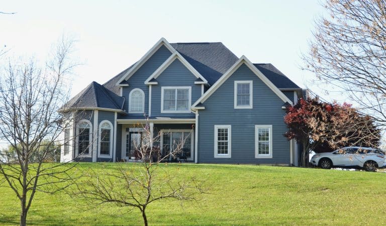 Large blue house on a grassy hill