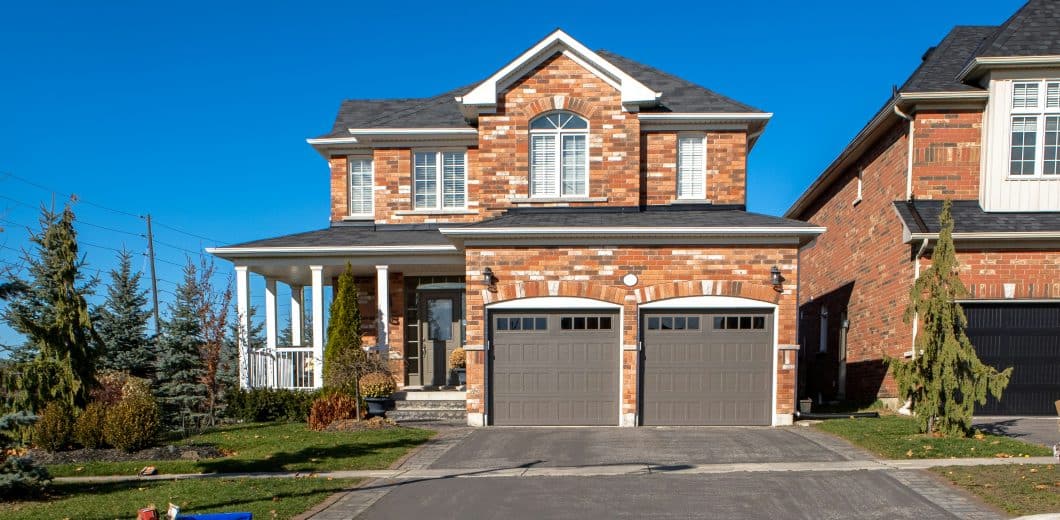 Brown and white house with an attached garage under a blue sky