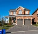 Brown and white house with an attached garage under a blue sky