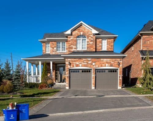 Brown and white house with an attached garage under a blue sky