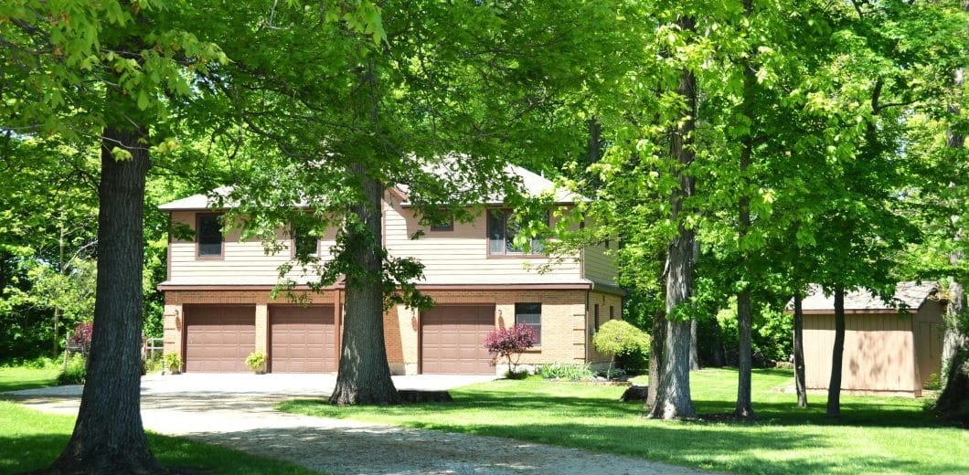 House with three garage doors surrounded by trees