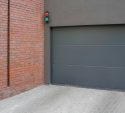 Modern grey sectional garage door beside a brick wall