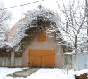 Snow covered trees around a garage with orange doors