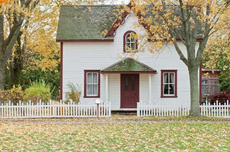 White home framed by golden maple trees on a cool fall morning