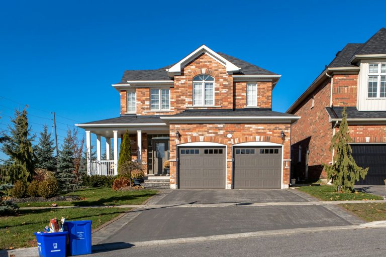 Brick home with two grey garage doors in late fall
