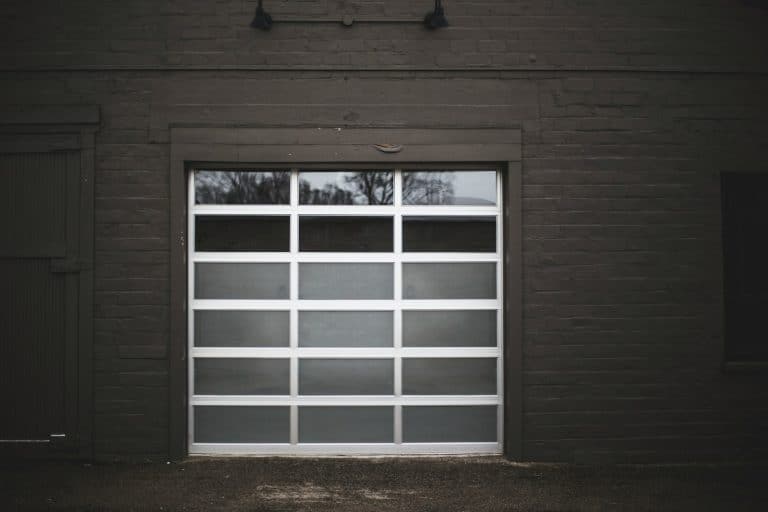 Glass panel garage door on a dark brick garage