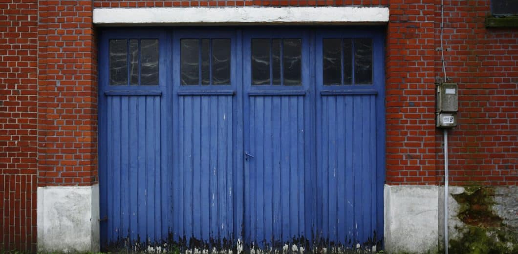 Blue carriage garage doors with window panes on a brick building