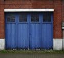 Blue carriage garage doors with window panes on a brick building