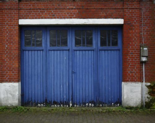 Blue carriage garage doors with window panes on a brick building
