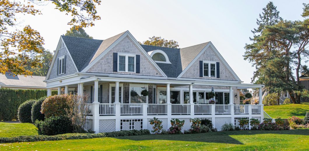 Elegant shingle style home with a manicured lawn in early fall