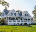 Elegant shingle style home with a manicured lawn in early fall