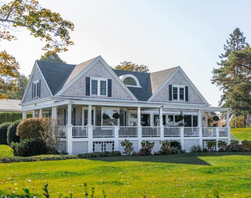 Elegant shingle style home with a manicured lawn in early fall