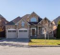 Stone home with two garage doors framed by a golden autumn tree