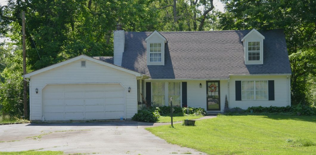 Older white garage door with visible panel wear on a family home