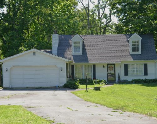 Older white garage door with visible panel wear on a family home