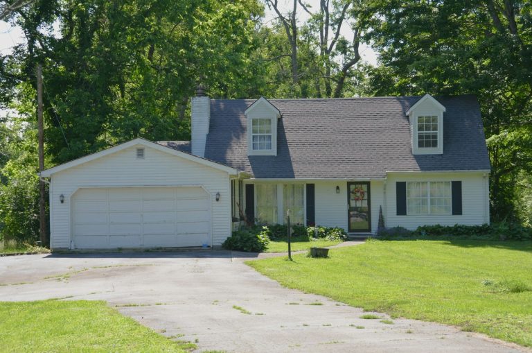 Older white garage door with visible panel wear on a family home