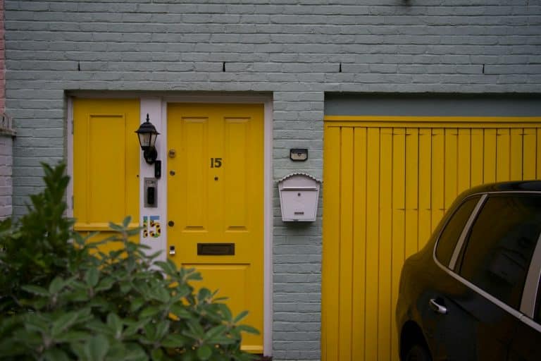 Paneled garage door and entry doors on a painted brick home