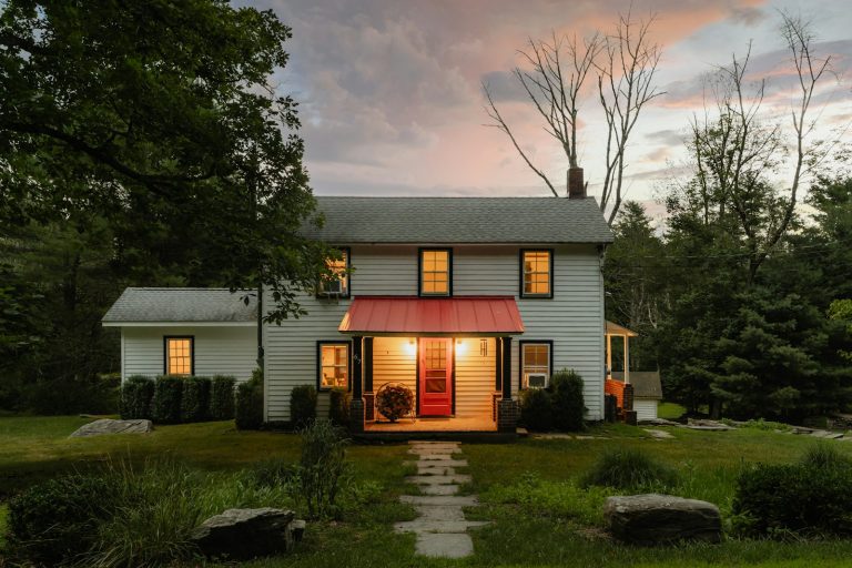 White farmhouse at dusk with a lit front porch