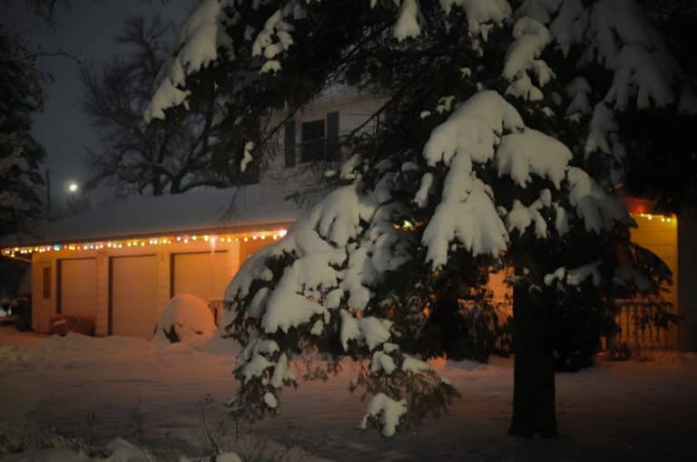 Snow covered yard and garage doors on a cold winter night