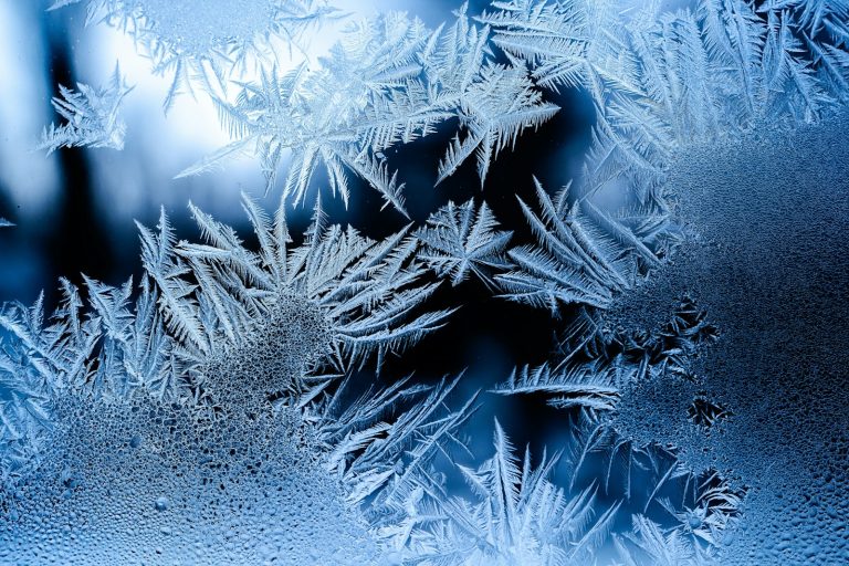 Frost crystals formed across a cold window pane in winter