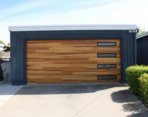 Low flat roofed detached garage with a wood clad sectional door