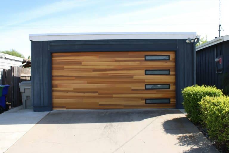 Low flat roofed detached garage with a wood clad sectional door
