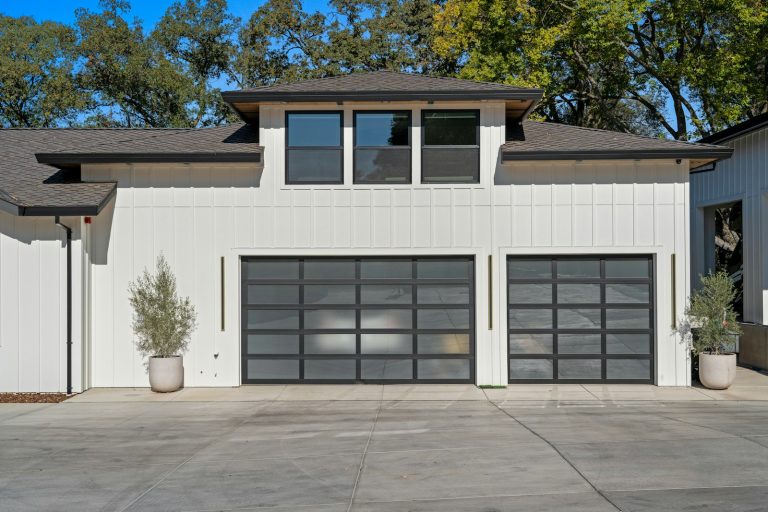 Full view glass panel garage doors on a modern white house