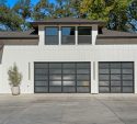 Modern white home with two full view glass panel garage doors