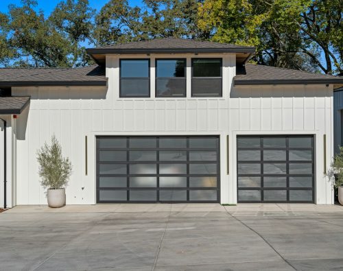 Modern white home with two full view glass panel garage doors